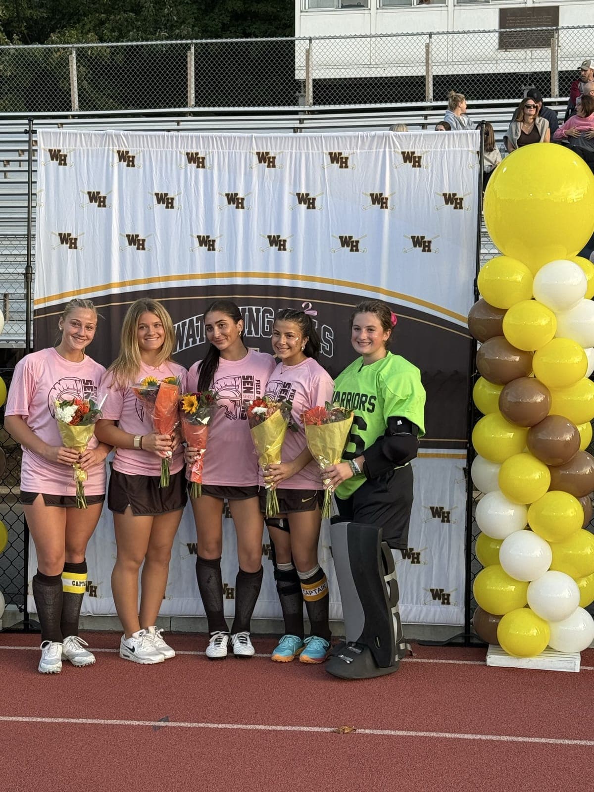 Watchung Hills field hockey seniors, two wearing captain armbands, are honored with bouquets.