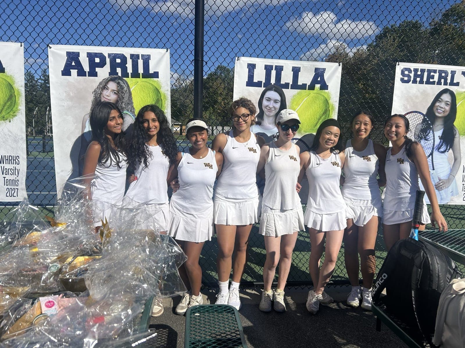 Watchung Hills varsity girls tennis seniors pose in front of their senior banners.
